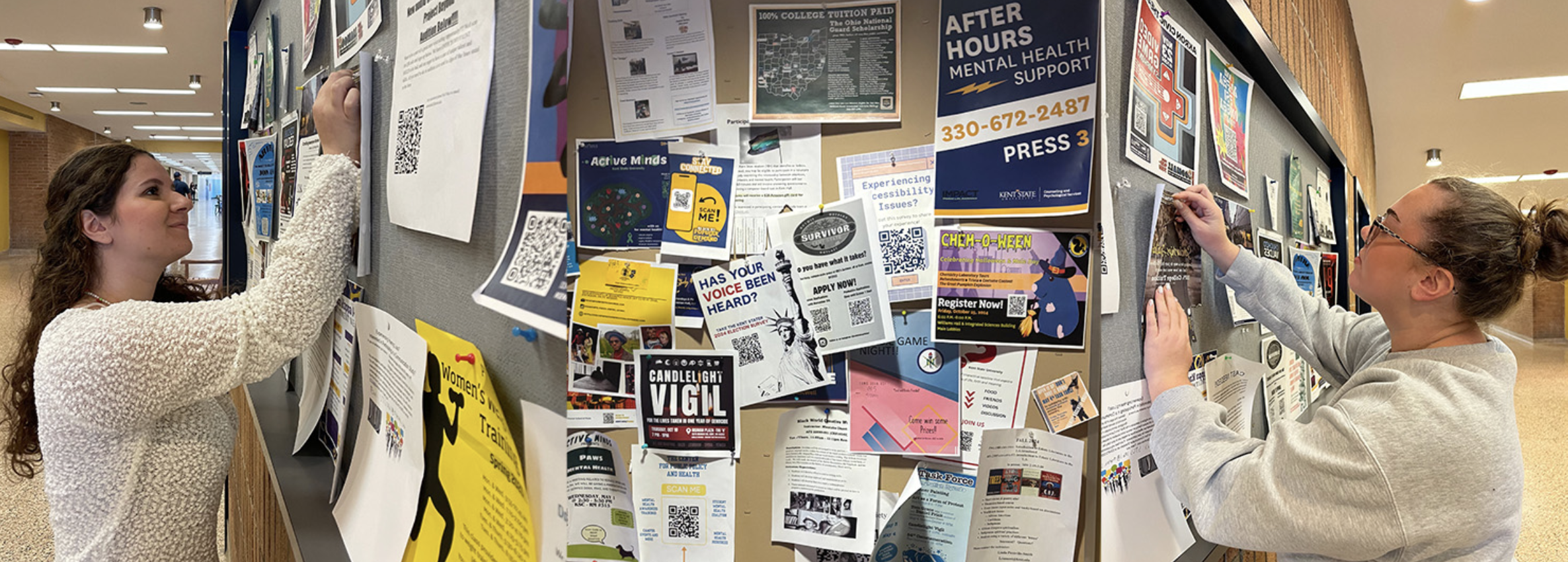 Student pins a flyer on a bulletin board